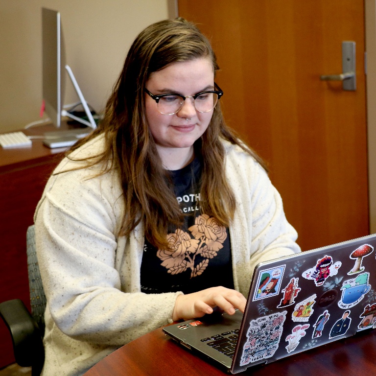 Gracie Lyons working on laptop during internship experience. 